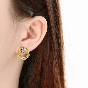 Detail of twisted knot earrings in gold and silver finish worn by a model