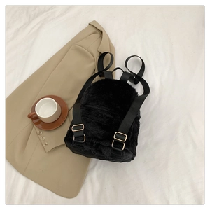 Detail view of a black faux shearling mini backpack with soft texture and golden buckles