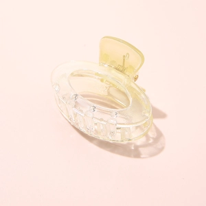 Detailed view of a small gradient yellow acetate shark hair clip on pink background