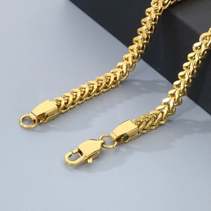Detailed macro shot of a golden stainless steel franco chain with a secure lobster clasp