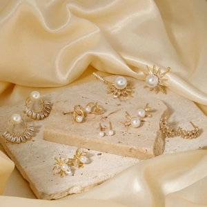 Elegant gold pearl and zircon stud earrings set displayed on luxury gold silk background