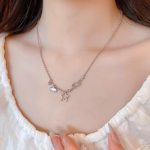 Detail of silver ball chain necklace with star, cloud and wing charms on a female model