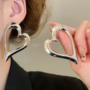 Detail showing large hollow heart earrings with polished silver metal finish on model