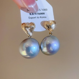 Detail view of heart-shaped gold studs with large lustrous pearls and iris effect
