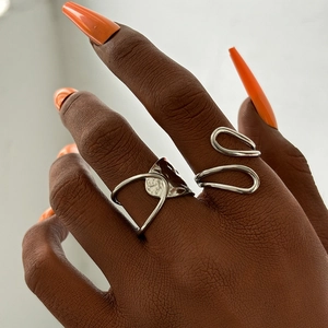 Detail view of two silver irregular geometric rings worn by a model in a layered style