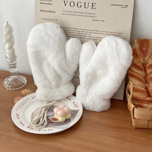 Detail of soft white plush mittens with a convenient neck strap on a cozy wooden table