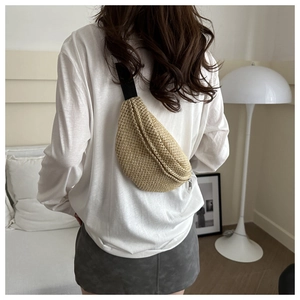 Sac de poitrine en paille tressée kaki avec sangle noire porté par un mannequin en intérieur