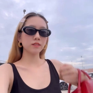 Fashionable model wearing gold spiral earrings and black oval sunglasses in a city street setting