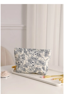 Floral canvas makeup bag on a marble tray with delicate flower and brush accents
