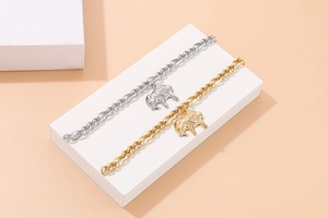 Detailed view of gold and silver elephant charm bracelets on a minimalist white display