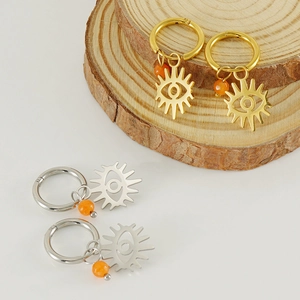 Detailed macro of gold and silver sunburst evil eye earrings with orange bead accents