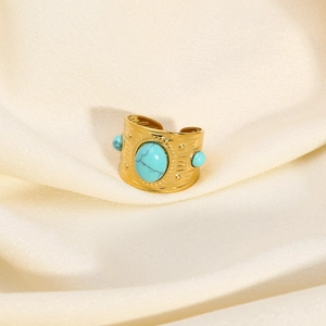 Close-up of vintage gold turquoise ring on elegant beige silk fabric background