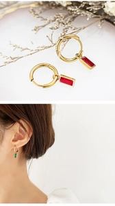 Detail of gold huggie hoop earrings with rectangular emerald and ruby gemstones
