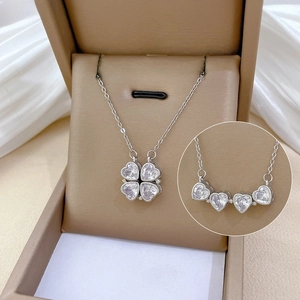 Detail of silver magnetic necklace transforming from four-leaf clover to four-heart shape