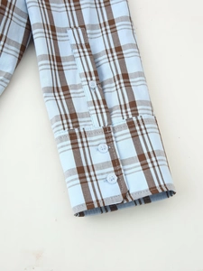 Detail shot of blue and brown checkered shirt cuffs with three transparent buttons