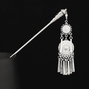 Close-up of silver Hmong hairpin featuring sun patterns and dangling metal tassels