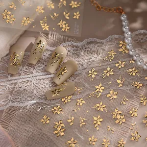 Macro detail of gold flower nail art stickers with embossed floral patterns on matte nails