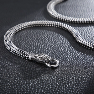 Dettaglio macro della chiusura a testa di serpente argento e catena intrecciata su pelle nera