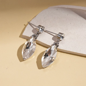 Detailed close-up of crystal leaf drop earrings on a stone texture background