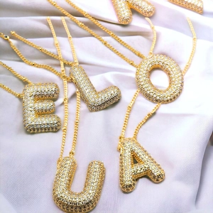 Détail des pendentifs lettres E, L, O, U, A en or 18 carats avec zircons cubiques