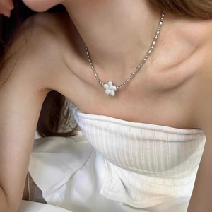 Minimalist silver flower pendant necklace with white petals and diamond detail on model