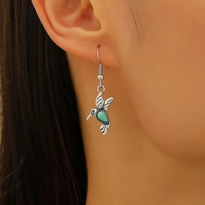 Close-up of hummingbird drop earring with turquoise stone and silver vintage wings