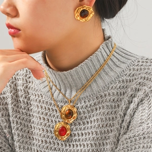 Detailaufnahme von Vintage-Goldhalskette und Ohrringen mit Bernstein und roten Edelsteinen