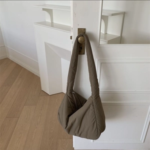 Detailed view of dark brown quilted tote bag hanging on a white door handle