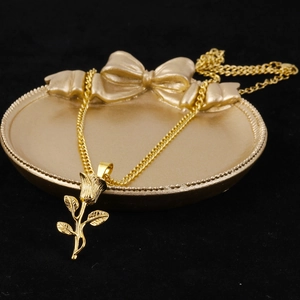 Detail shot of golden 3D rose pendant on a bow tray with elegant black background