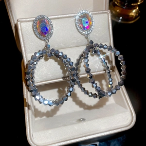 Gros plan de grandes boucles d'oreilles strass avec cristaux irisés sur boîte à bijoux