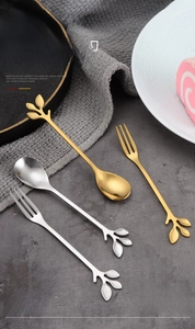 Macro shot of elegant leaf-shaped gold and silver stainless steel dessert spoons and forks