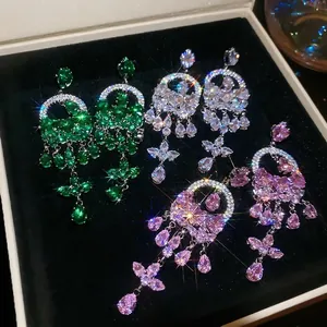 Three pairs of elegant zircon tassel earrings in green, purple, and white in a jewelry box
