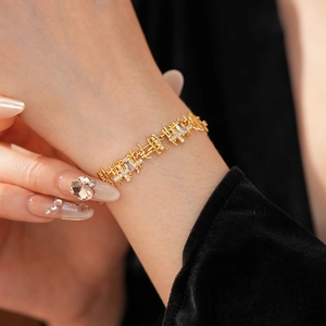 Détail d'un bracelet de luxe doré avec cristaux carrés sur un poignet de femme