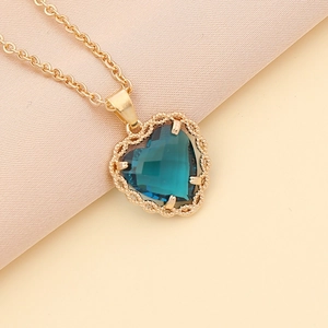 Golden necklace with a blue heart-shaped gemstone and intricate cutout frame
