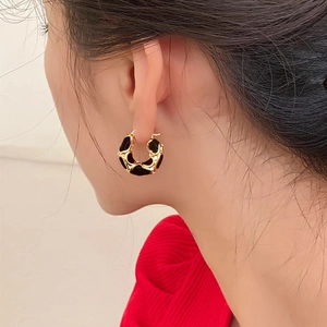 18K gold plated C-shaped earrings with black enamel and zircons worn by a model