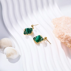 Detail of leaf-shaped gold earrings with green enamel inlay and pearl accents