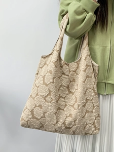 Detailed view of beige tote bag featuring 3D floral embroidery and embossed rose patterns