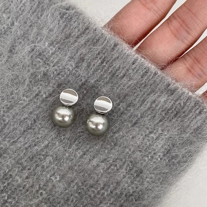 Minimalist irregular silver metal disc and grey pearl drop earrings on knit background