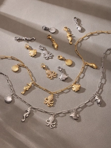 Artistic detail of gold and silver ocean charms like octopus and seahorse on grey background