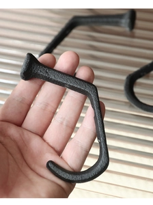 Macro detail of industrial black cast iron rail nail hook with grainy matte texture