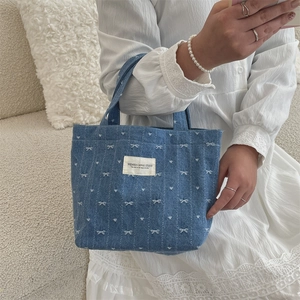Détail du sac en jean avec nœud blanc et broderie cœur sur robe en dentelle