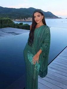 Elegant emerald green V-neck maxi dress with sequins and tassel hem on pool background