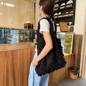 Close-up of a black oversized canvas tote bag with textured fringe and tassel details