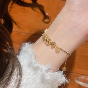 Nahaufnahme des 18k vergoldeten Armbands mit Münzanhängern und Glanz-Strasssteinen