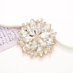 Elegant gold flower rhinestone brooch with sparkling crystal petals on a white surface