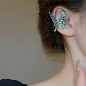 Detail of vintage blue enamel butterfly ear cuff on ear with gold metal edges