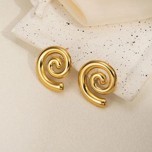 Detailed view of gold spiral geometric earrings on ceramic tray with silk background