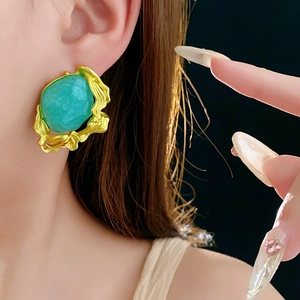 Close-up of vintage gold emerald earring with irregular frame on model's ear