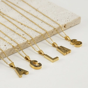 Detail of gold letter pendants A C L M S with black linear textures and 18K plating