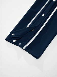 Detail of navy knit joggers showing white side stripes and silver snap buttons